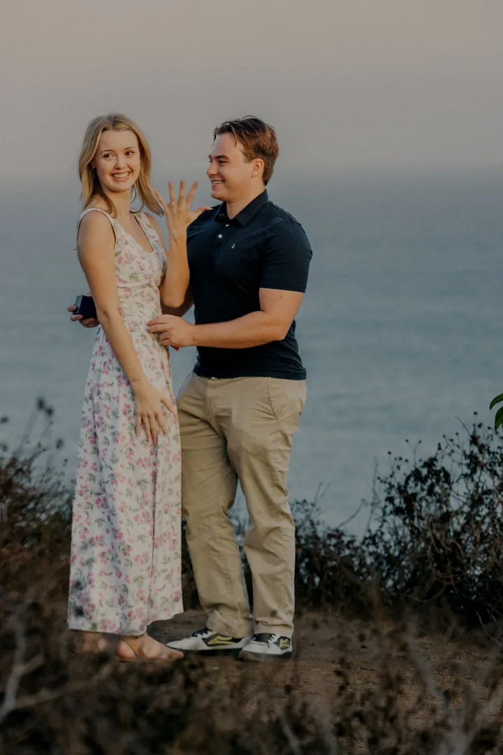 Kayley showing her ring beside Jack on the coastal bluff