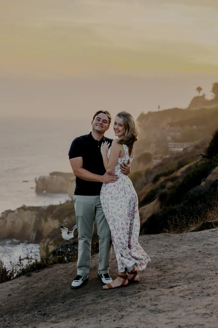 Kayley and Jack standing together above the coastline at sunset