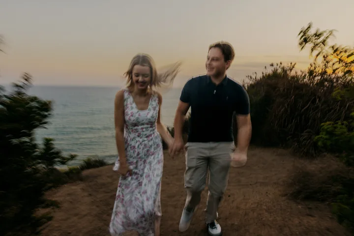 Kayley and Jack walking toward the camera with the sea behind them