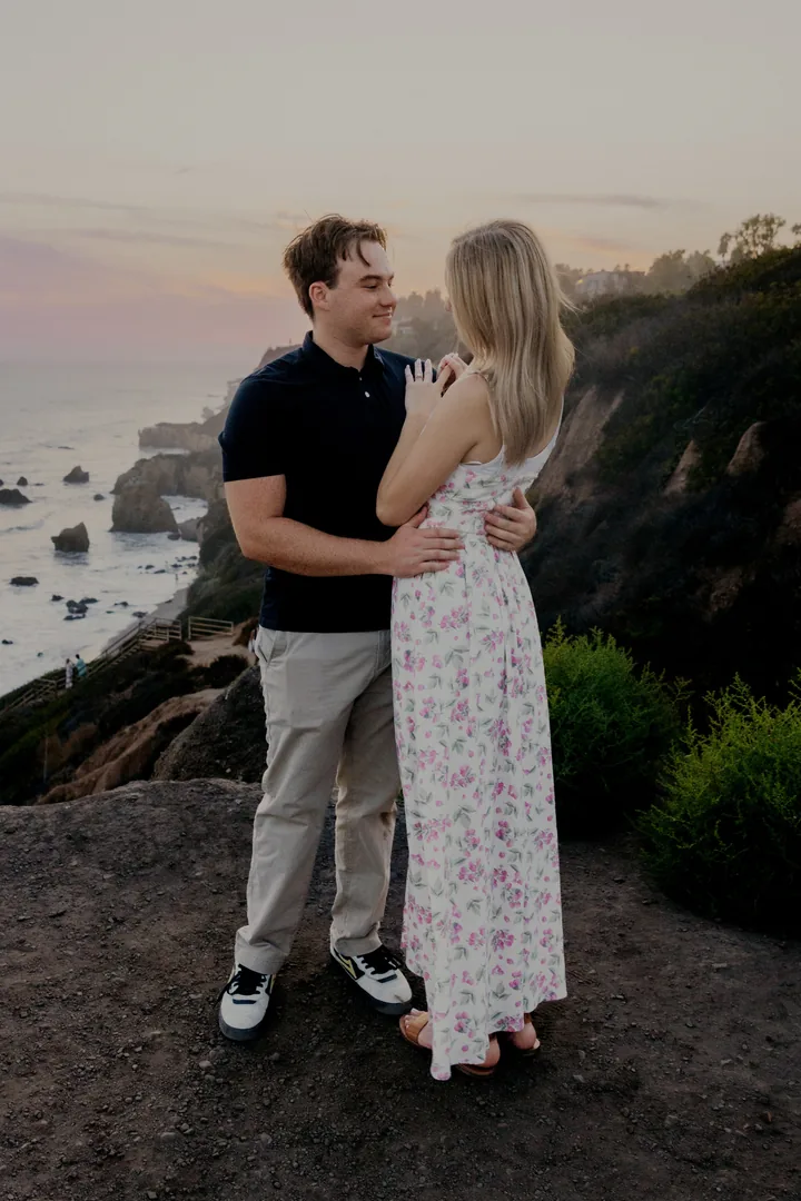 Kayley and Jack facing each other above the coastline at dusk