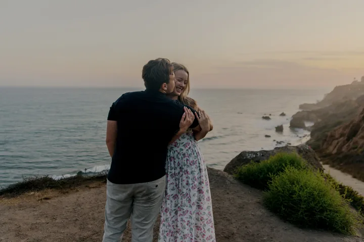 Kayley and Jack holding each other beside the coastal path at sunset
