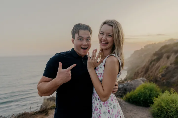 Kayley showing her ring while Jack points toward it and smiles