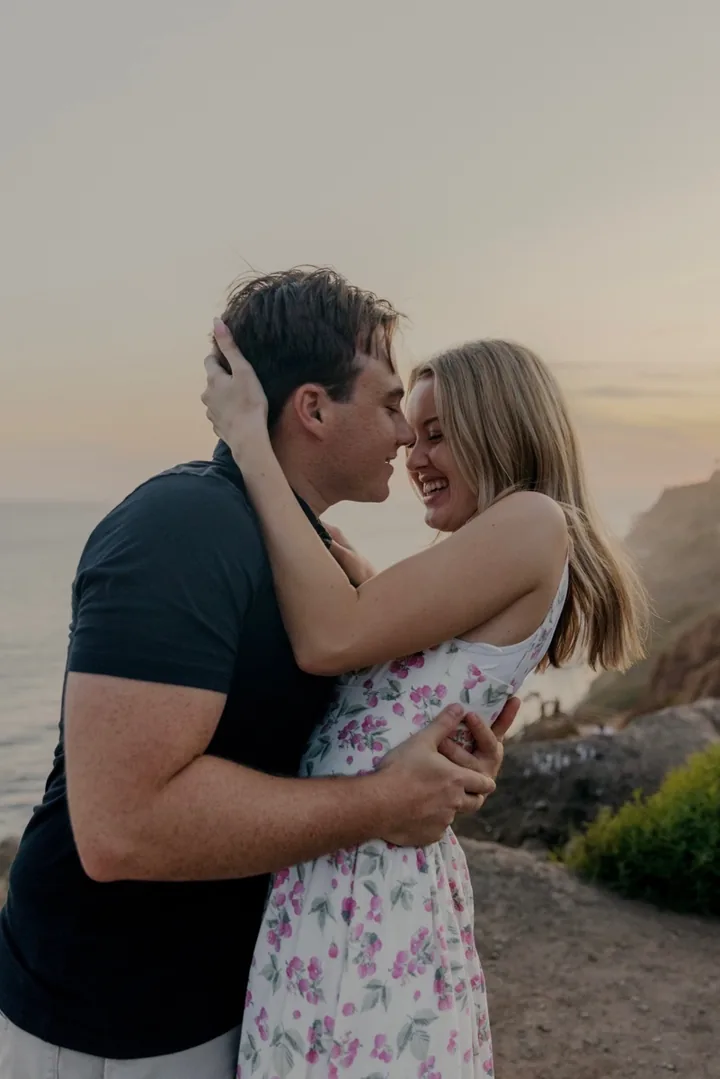 Kayley and Jack leaning close together and smiling by the ocean