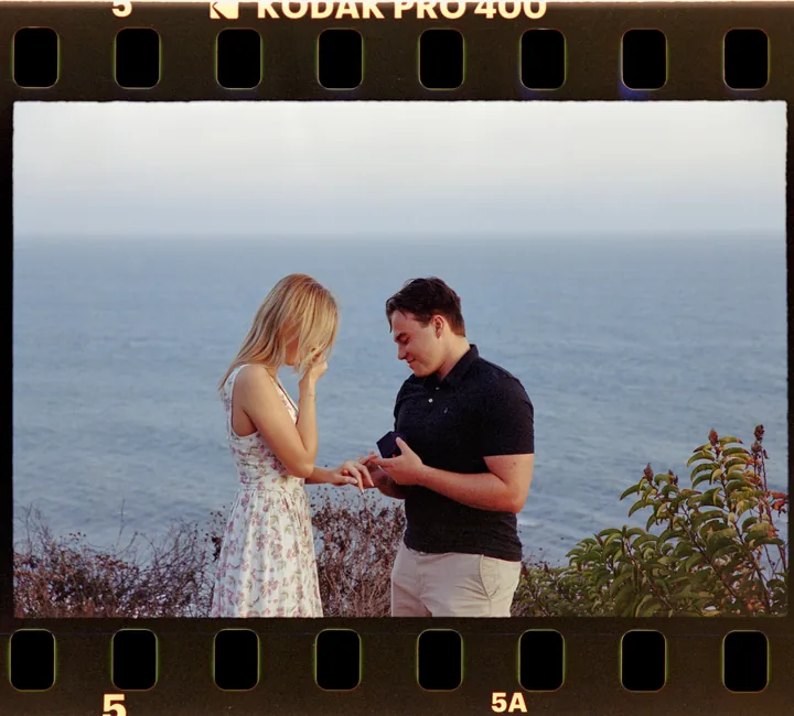 Film-framed photograph of the proposal with the ocean behind Kayley and Jack
