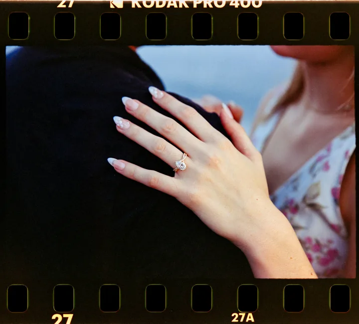 Film-framed close-up of Kayley's engagement ring against Jack's shoulder